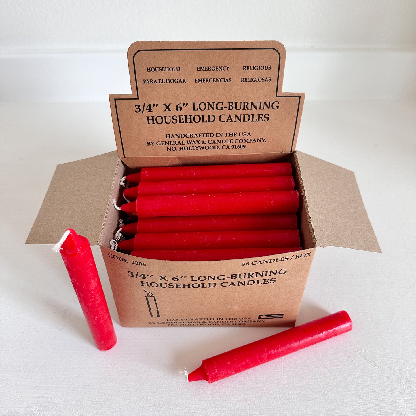 Box of red household candles with a cardboard box on a white background