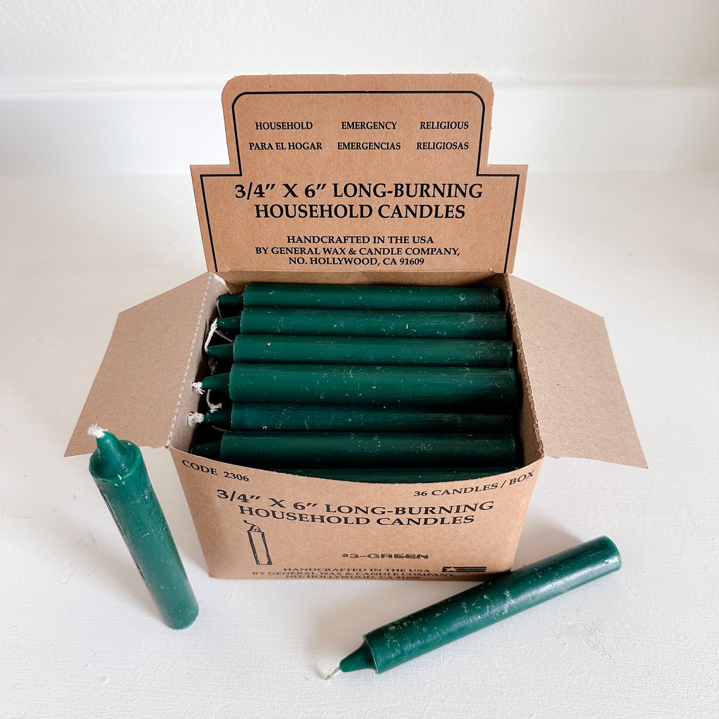 Box of green household candles with a cardboard box