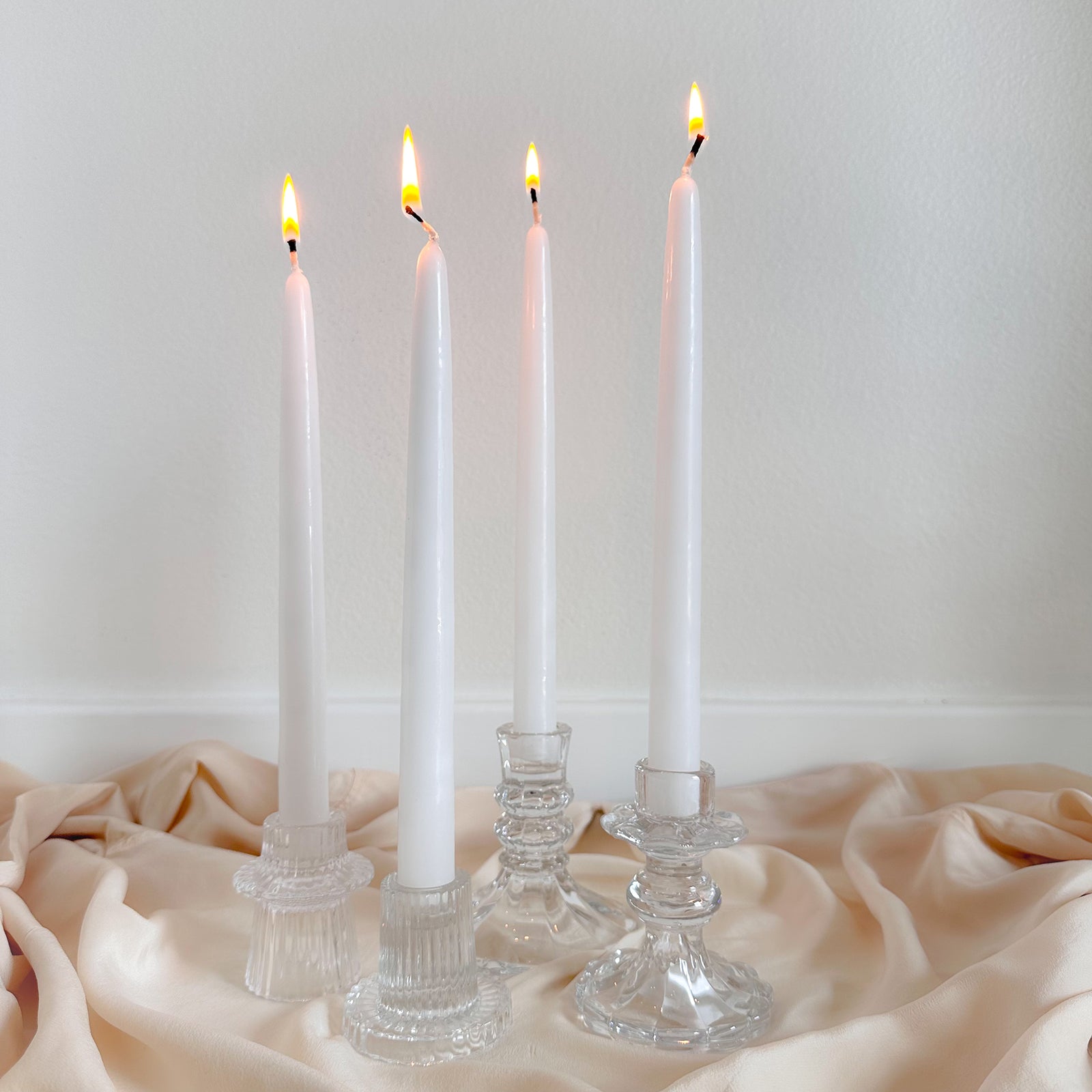 Four white candles in glass candlesticks