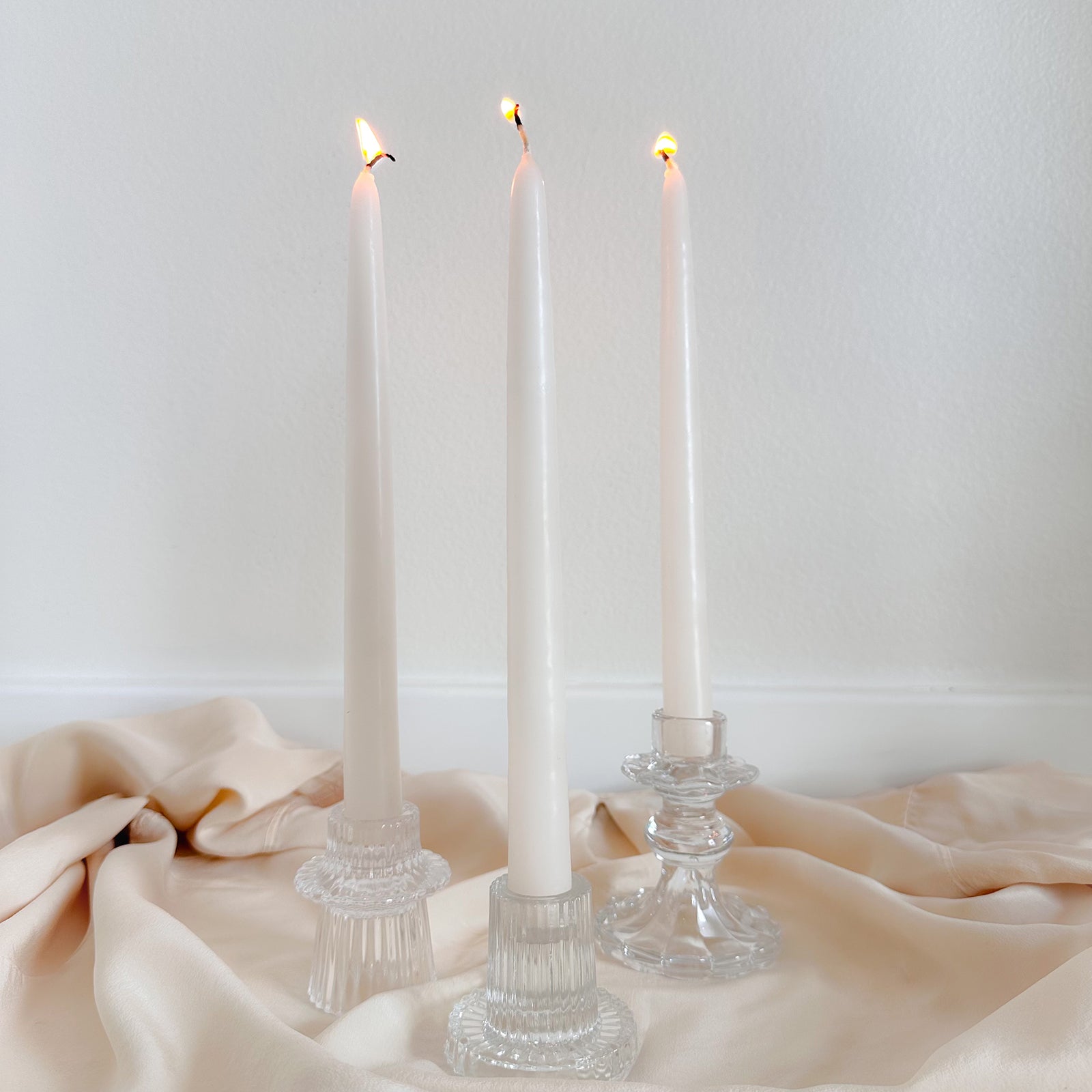 Three lit candles in glass candlesticks
