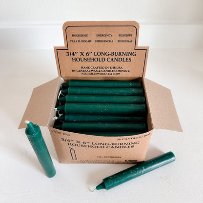 Box of green household candles with a cardboard box 