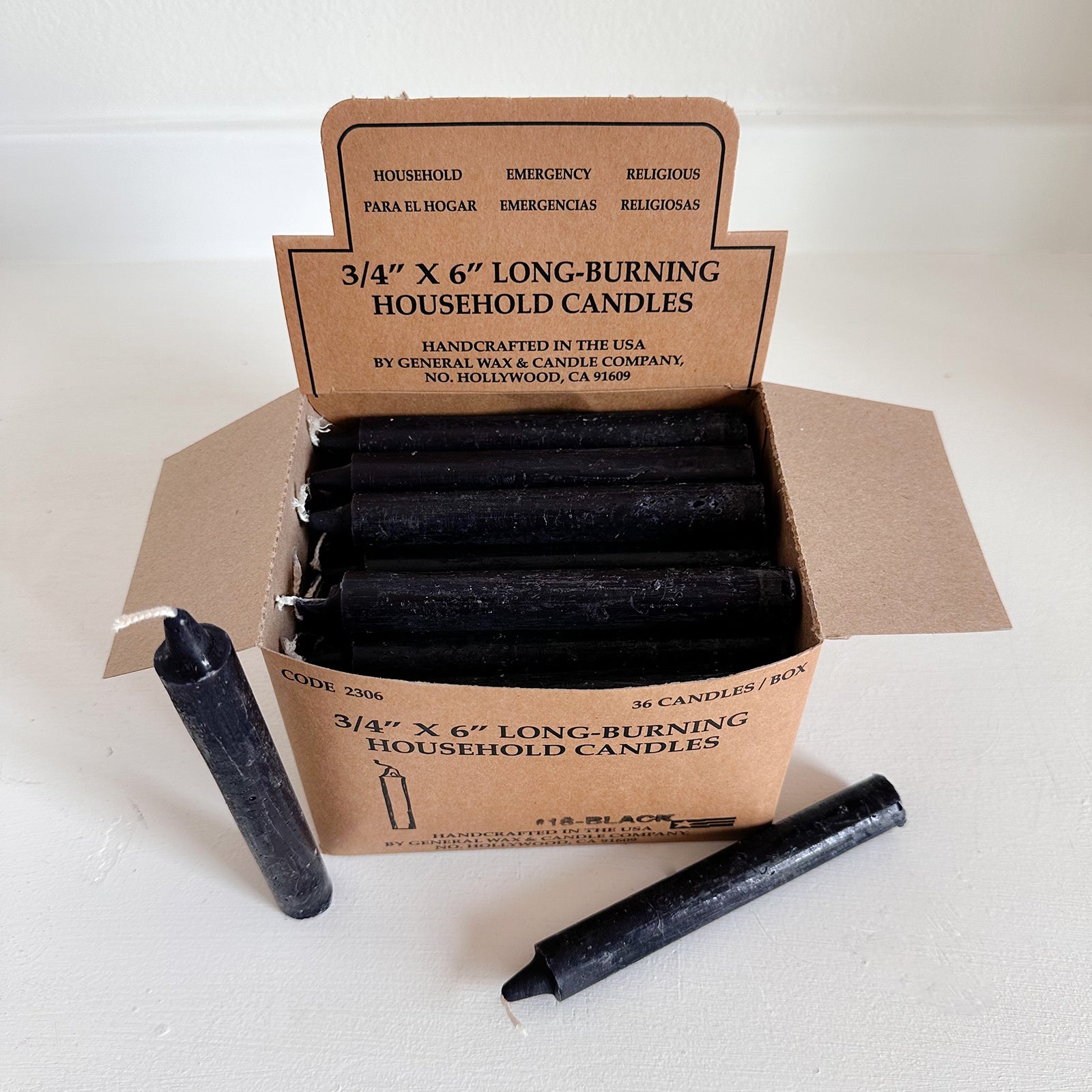 Box of black household candles with a cardboard box 