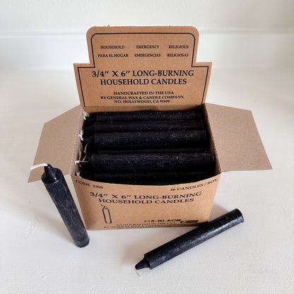 Box of black household candles with a cardboard box 