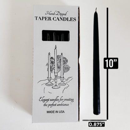 Black taper candle next to its packaging with dimensions 